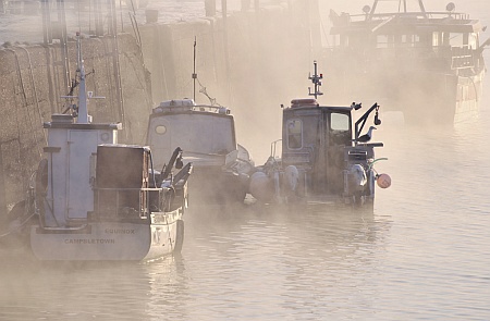 [Mist drifting around moored boats]